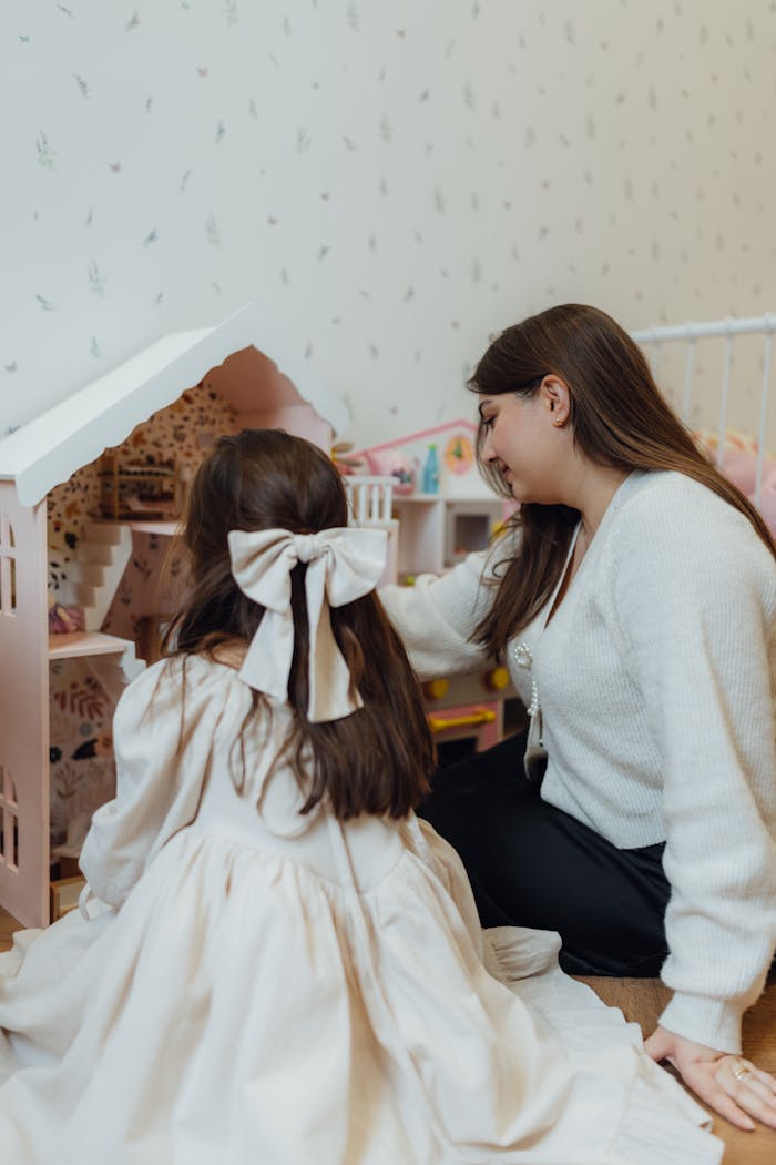About A mother and daughter enjoying quality time playing with a dollhouse at home.